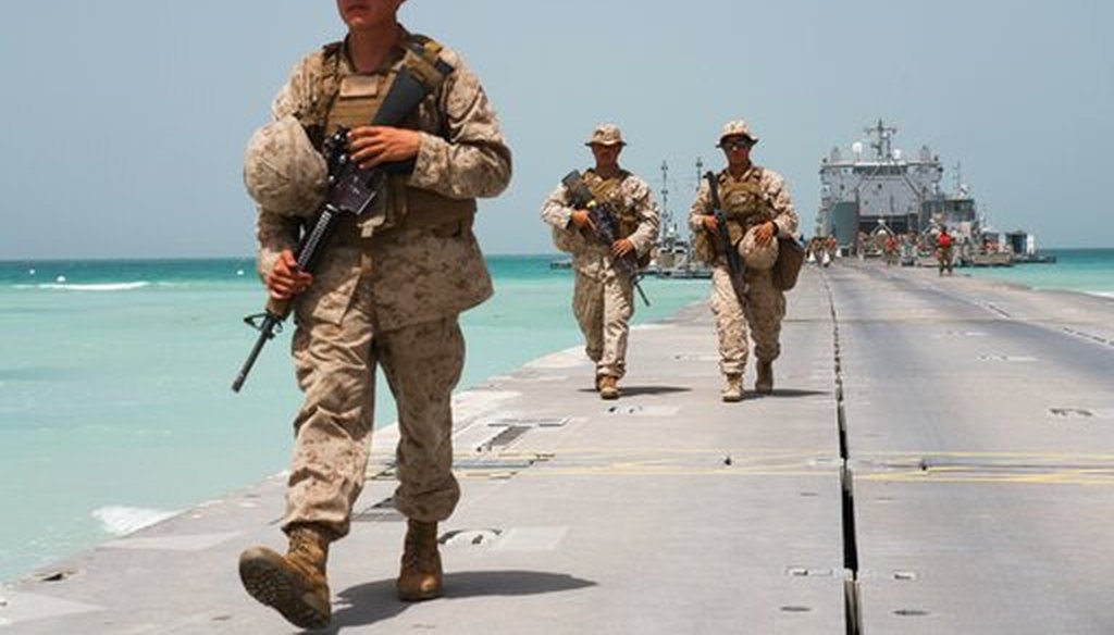 U.S. Marines walk down a removable Trident Pier leading to an American ship docked near a military base in al-Hamra, United Arab Emirates, on March 23, 2020. (AP)